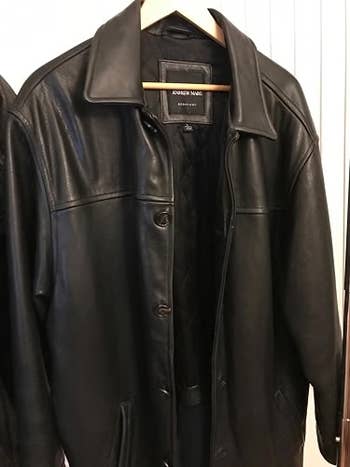 Black leather overgarment hanging connected a woody hanger successful a closet
