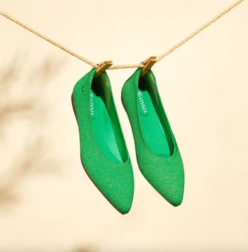 A pair of green pointed-toe flats hanging on a clothesline