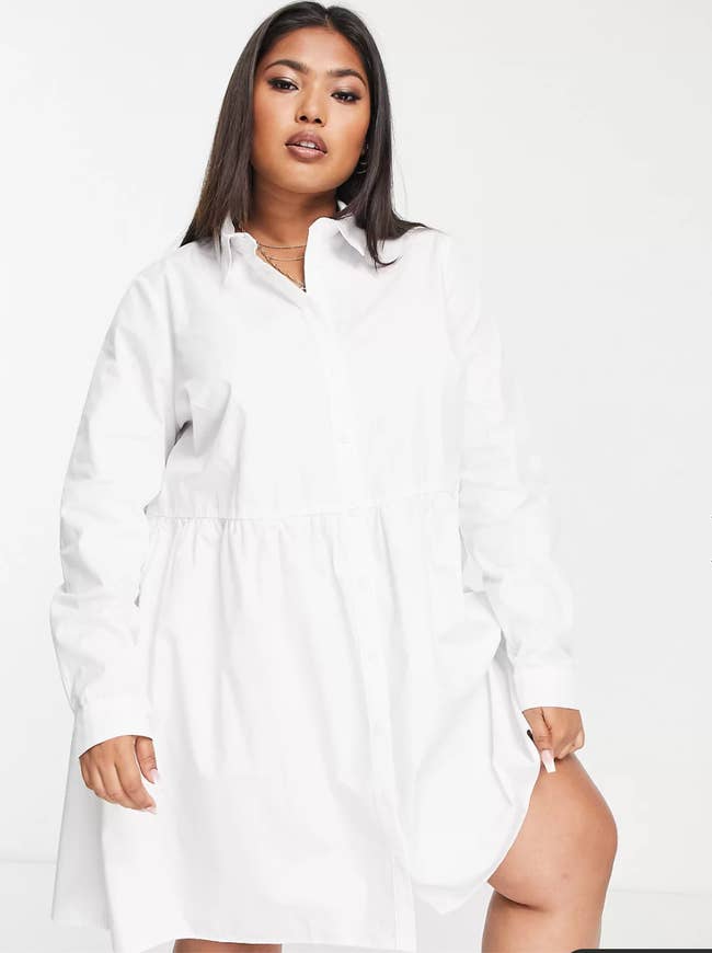 a model poses in the white button down dress