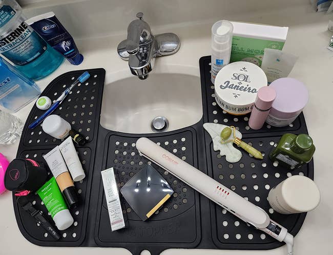 A variety of skincare products and tools arranged on a sink-top organizer
