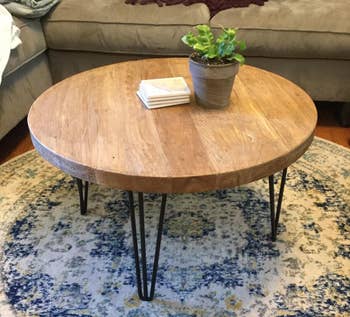 Reviewer image of the brown round wood coffee table with a plant on top of it