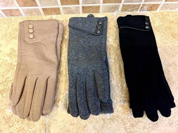 Three pairs of gloves in beige, gray, and black