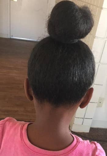 back of reviewer's child's head, which shows their hair without knots and tied up into a bun