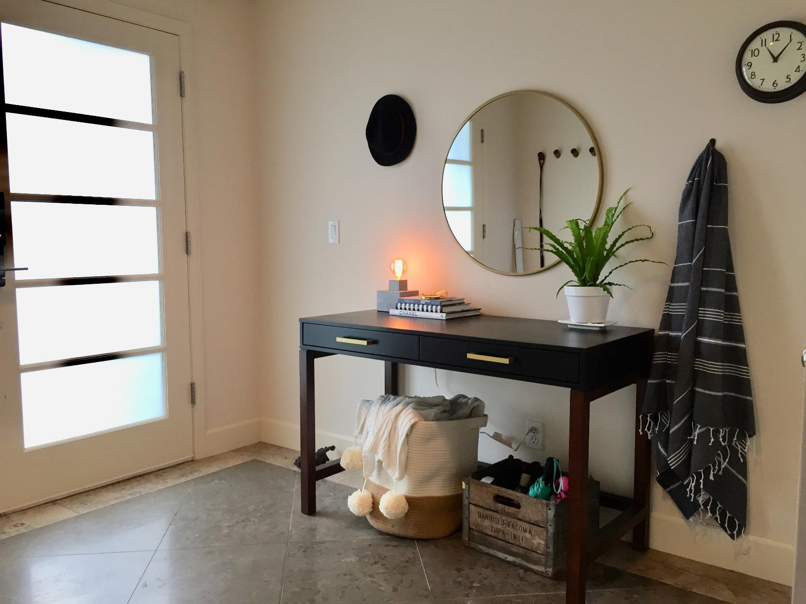 Entryway table with decor, lamp, and books above; basket with pom-pom throw and crate with shoes below for home organization ideas
