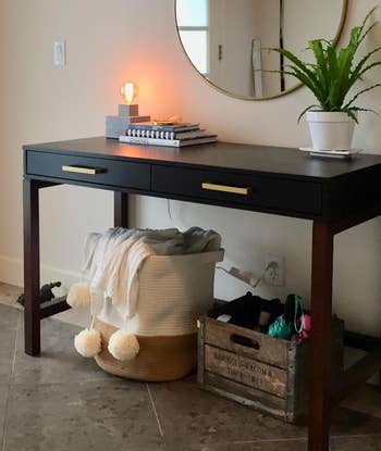 Entryway table with decor, lamp, and books above; basket with pom-pom throw and crate with shoes below for home organization ideas