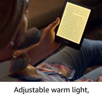 Model reading a book on the Kindle Paperwhite, which is illuminated so they can read in the dark