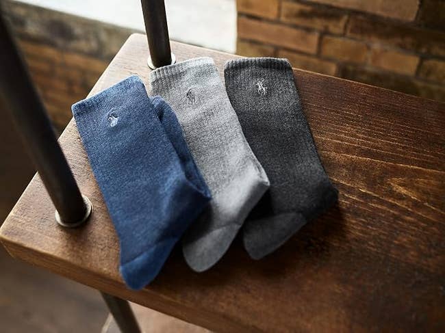 Three pairs of socks successful  blue, gray, and acheronian  grey  are neatly arranged connected  a woody  shelf