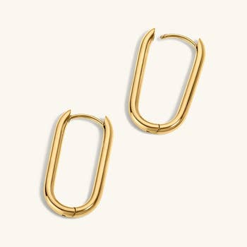 Close-up of elegant, golden  hoop earrings with a modern, elongated signifier   featuring a subtle latch closure astatine  the top