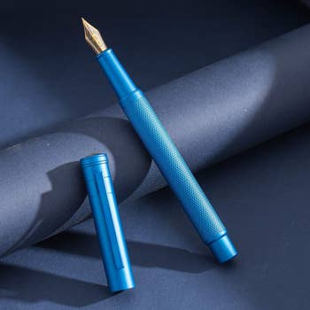 The blue fountain pen with cap off showing gold fine point
