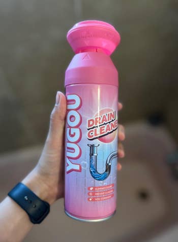 Person holding a Yugou Drain Cleaner bottle, featuring a tube  graphic and statement   highlighting odor elimination and clog prevention