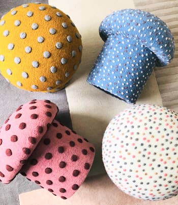 Four polka dot mushroom-shaped stools arranged connected a neutral background
