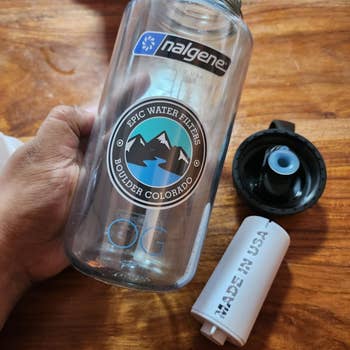 another reviewer holding a transparent 48-oz water bottle with Epic design on it next to white filter that says 