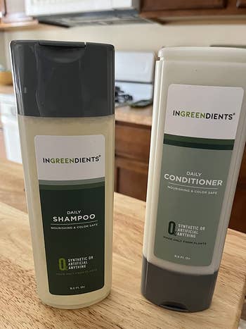 Reviewer image of green and white shampoo and conditioner on top of wooden table