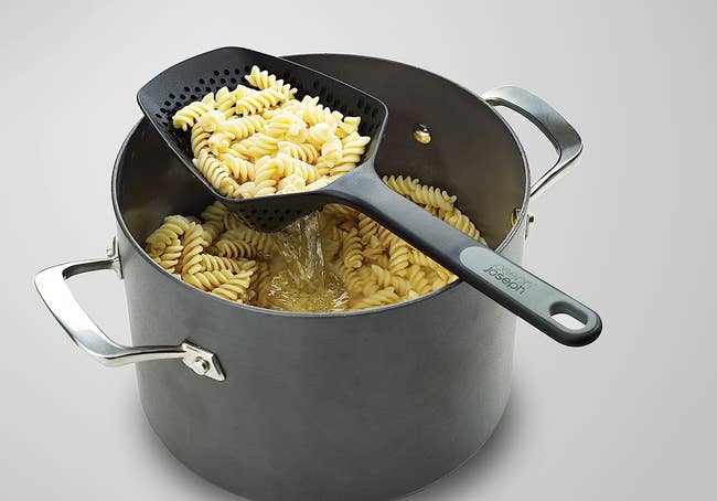the spoon being used to scoop out pasta in water 
