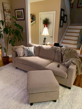 reviewer photo of a beige sectional couch with a matching ottoman at a slant in front of it