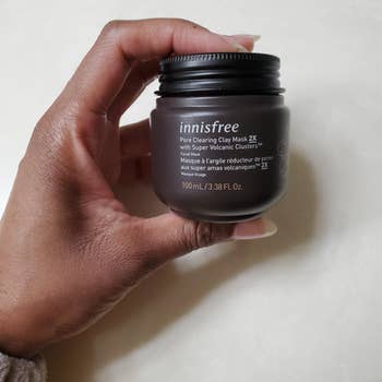 Person's hand holding a jar of Innisfree Pore Clearing Clay Mask 2X for skin care