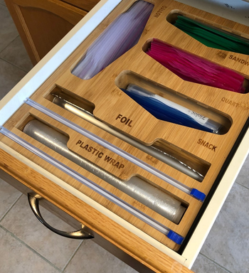 a wood organizer with six different opening that read plastic, foil, sandwich, snack, and quart.