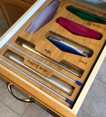 a wood organizer with six different opening that read plastic, foil, sandwich, snack, and quart.