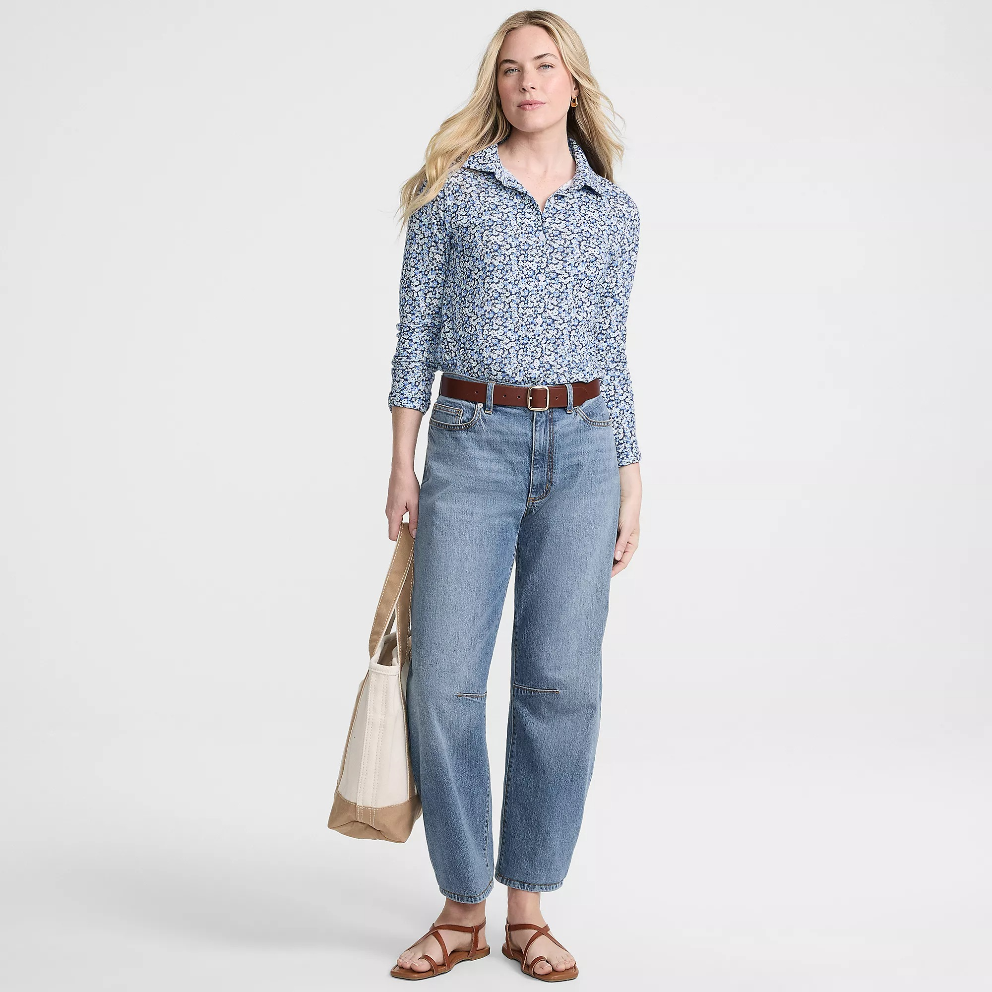 Person successful  a patterned, long-sleeve garment  with jeans and sandals, holding a tote bag. Casual and stylish outfit for a buying  day