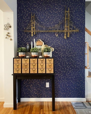 A dresser with multiple drawers against a wall with navy constellation wallpaper