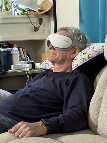 Person relaxing connected  a recliner, utilizing a futuristic oculus  massager device