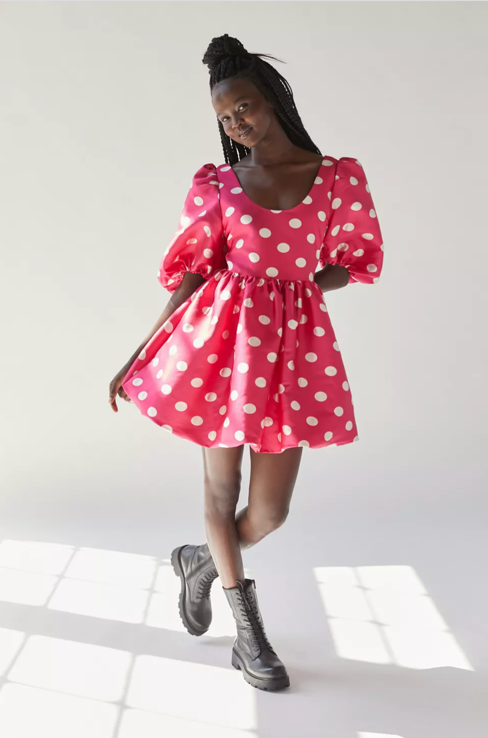 Model in mini hot pink dress with large white polka dots and puffy sleeves paired with black laced combat boots