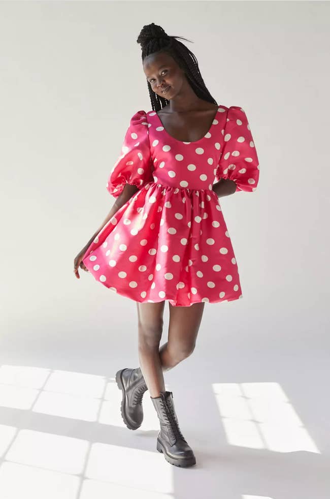 Model in mini hot pink dress with large white polka dots and puffy sleeves paired with black laced combat boots