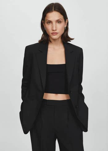 Model in a black blazer and crop top, suitable for professional or stylish casual wear