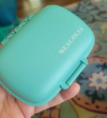 reviewer holding the teal pill organizer