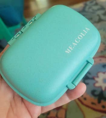 reviewer holding the teal pill organizer