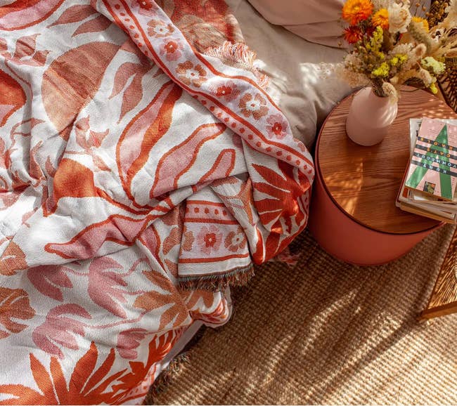 the orange, pink, and white floral patterned woven blanket on a bed