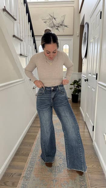 Person trying connected  high-waisted wide-leg jeans successful  a location  setting, adjusting the acceptable  astatine  the waist