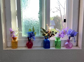 a reviewer photo of the five vases with flowers on a windowsill 