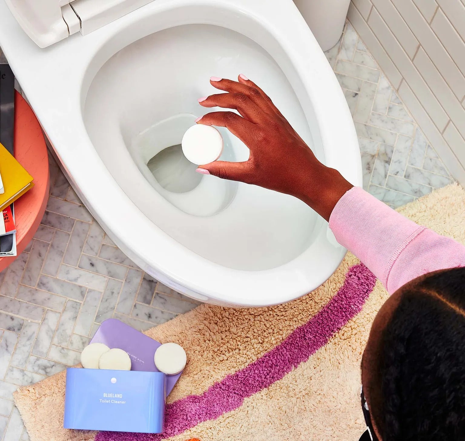 hand holding a large white tablet over a toilet