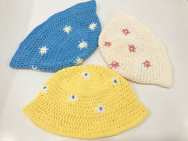 Yellow, blue, and. white crochet bucket hats with a small flower pattern