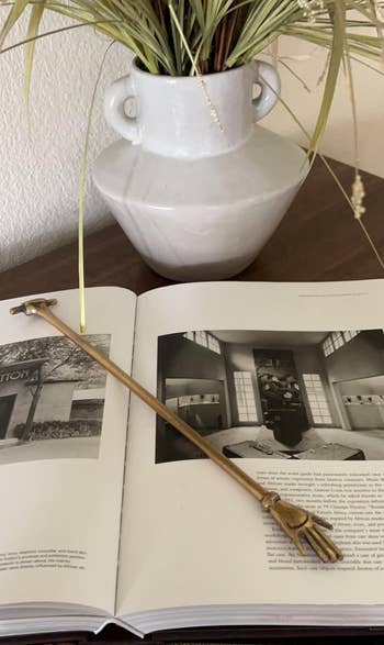 Open publication with vintage-style metallic bookmark, showing articles astir interior design, adjacent to a decorative achromatic vase