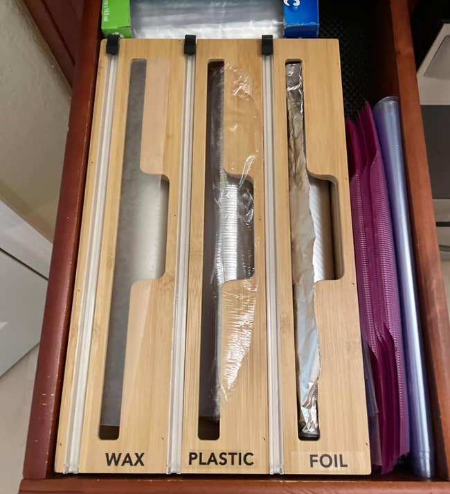 a reviewer shows the 3-slot organizer in their kitchen drawer and labeled with wax, plastic, and foil