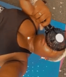 gif of reviewer using the black fan on their face after a workout