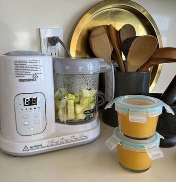 reviewer's baby food maker on a countertop next to two small containers of food it made