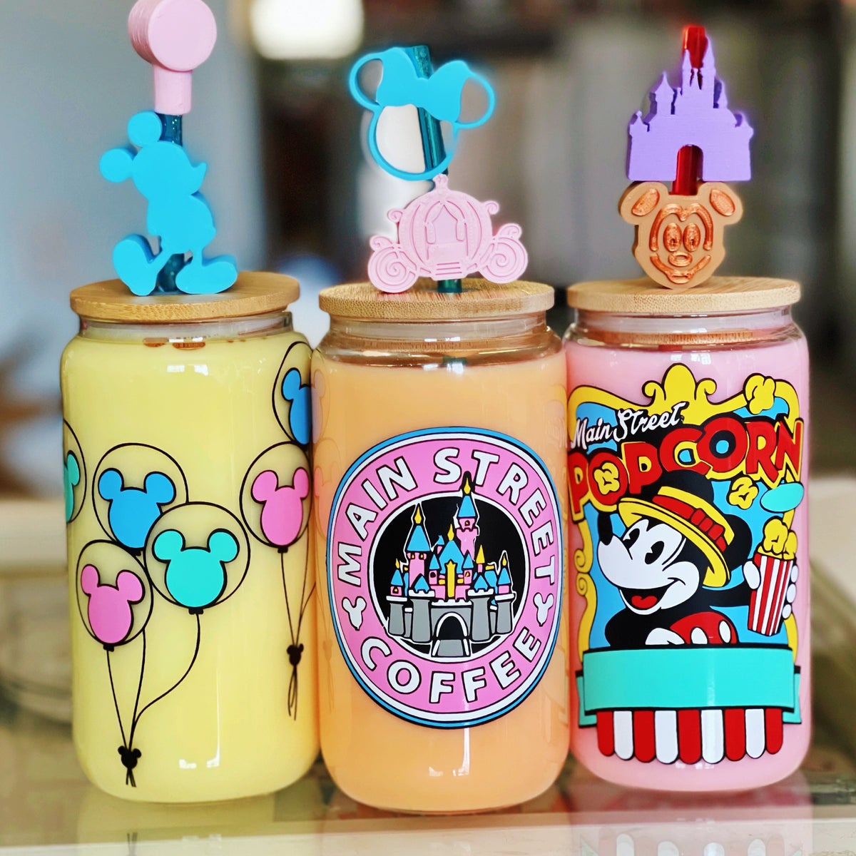 three glass cans each with a disney-inspired design on them