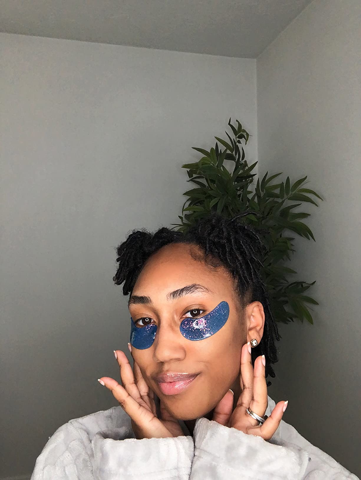 person wearing under-eye patches with a relaxed expression, posed successful  beforehand   of a plant