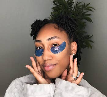 person wearing under-eye patches with a relaxed expression, posed successful beforehand of a plant