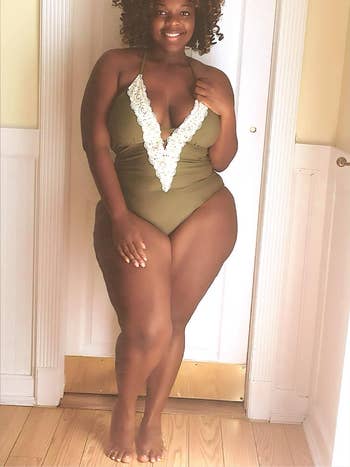 reviewer wearing an olive green bathing suit with white lace trim along the neckline