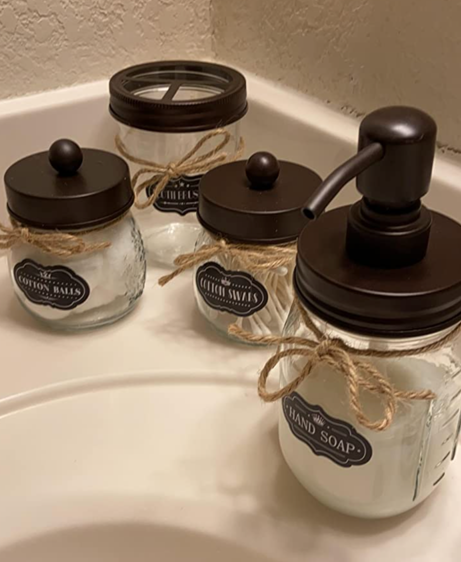 The clear glass holders with dark brown lids on a bathroom counter 