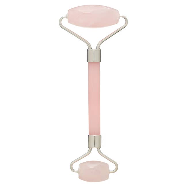 Facial roller with 2 roseate quartz ends and a metallic handle, utilized for skincare routines to massage and beforehand circulation