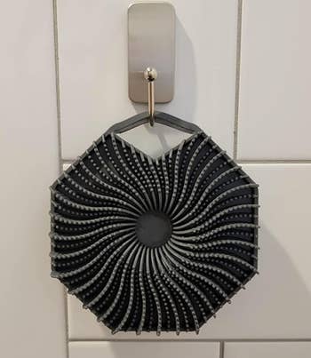 the scrubber hanging from a tiled shower wall 
