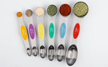 the six colorful measuring spoons each holding spices
