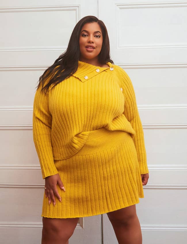 a model in a mustard colored yellow skirt with matching sweater