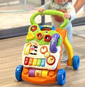 Baby playing with a colorful enactment   walker featuring buttons, dials, and a tiny  telephone, successful  a location  setting