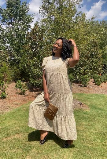 reviewer in a tiered maxi dress with a matching clutch, posing playfully outdoors